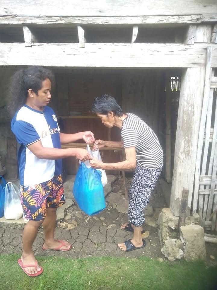 A woman receiving bags of supplies outside her home