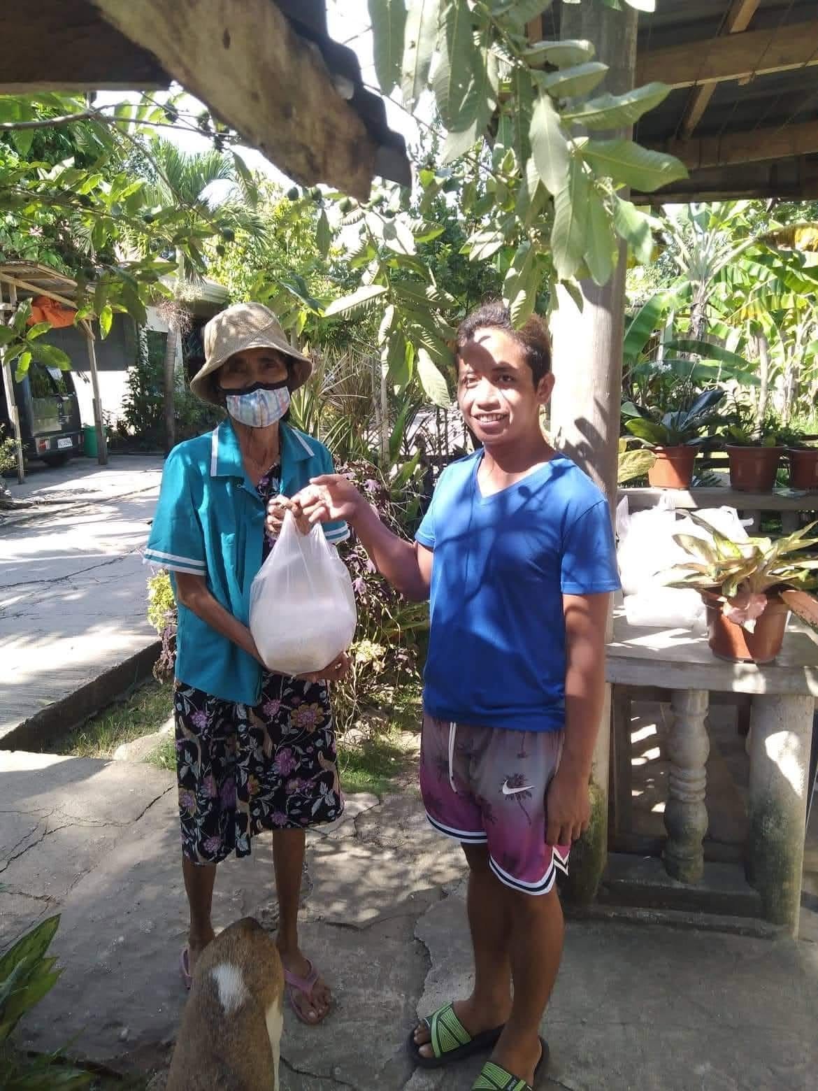 A woman and a volunteer holding a food package outdoors