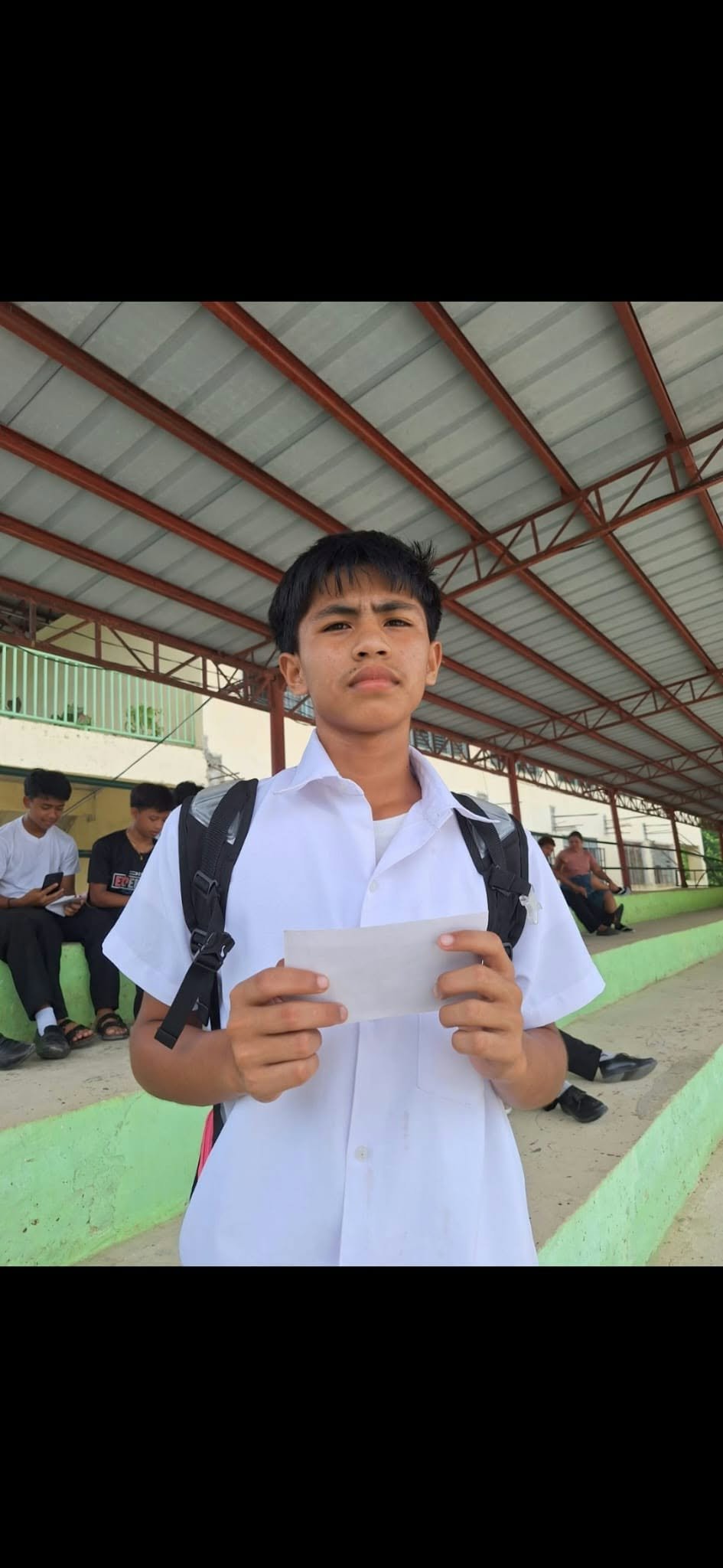 A student holding an envelope at a covered school venue
