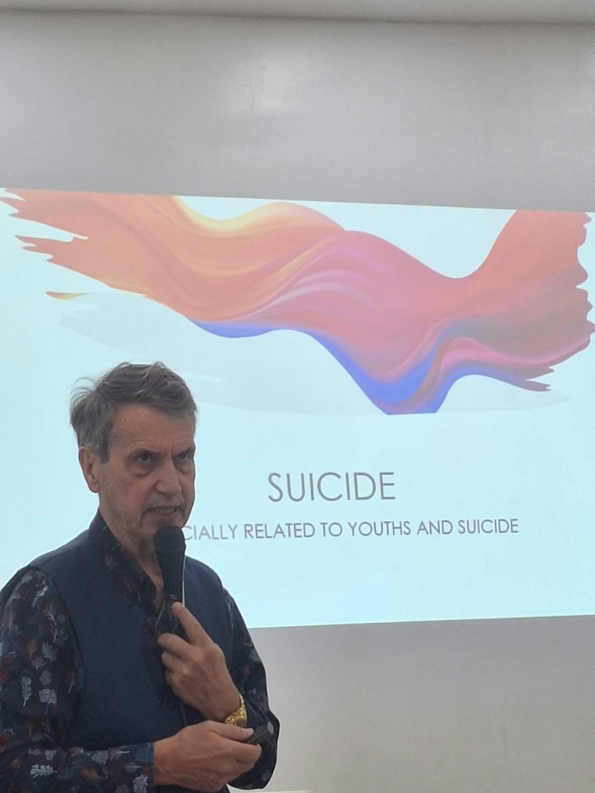 A speaker presenting a slide about suicide awareness