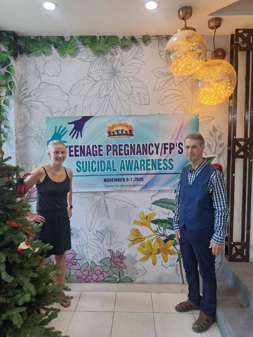Two people standing beside an awareness seminar banner